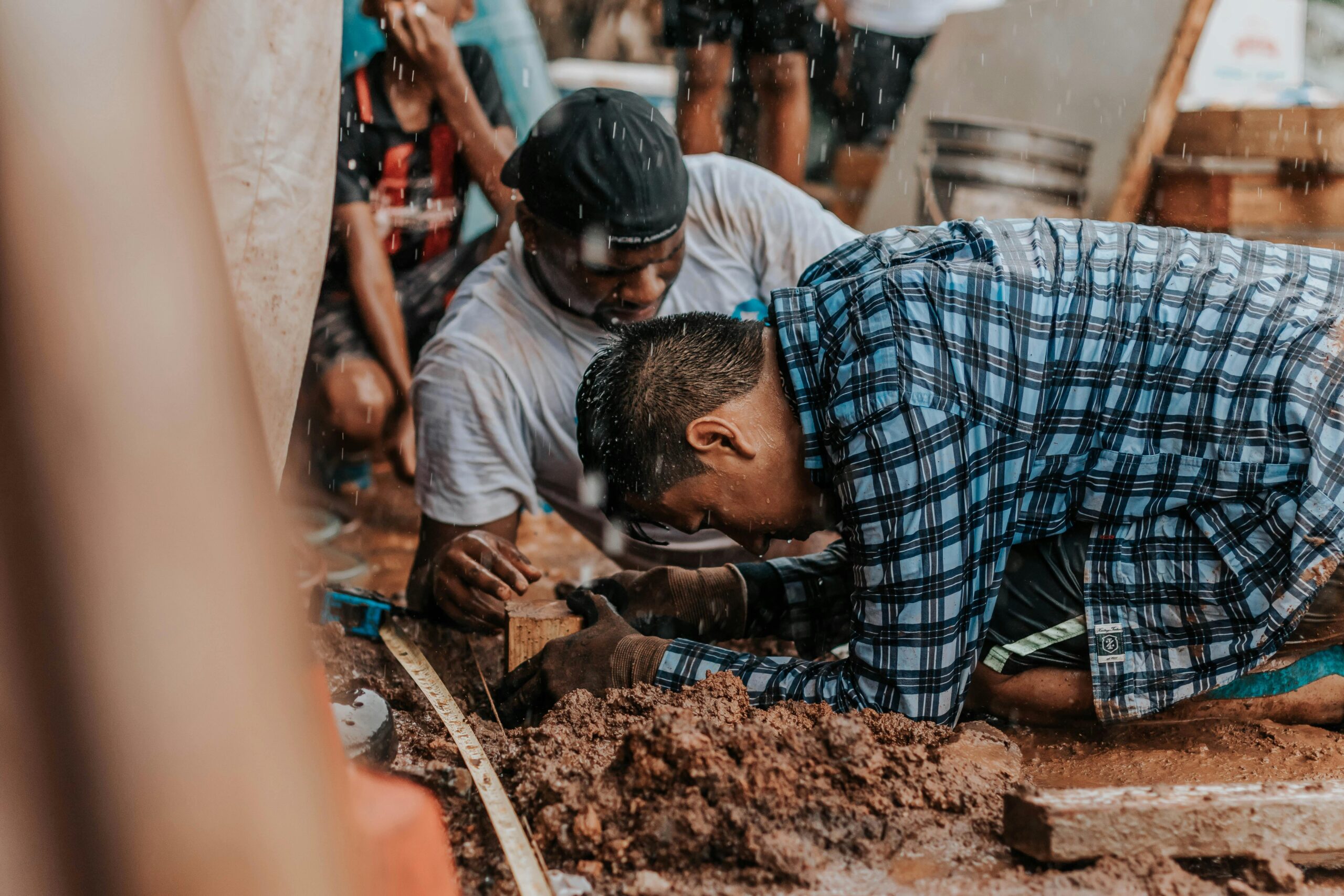 A group of men collaborating on a construction project in an outdoor setting with earthy tones.