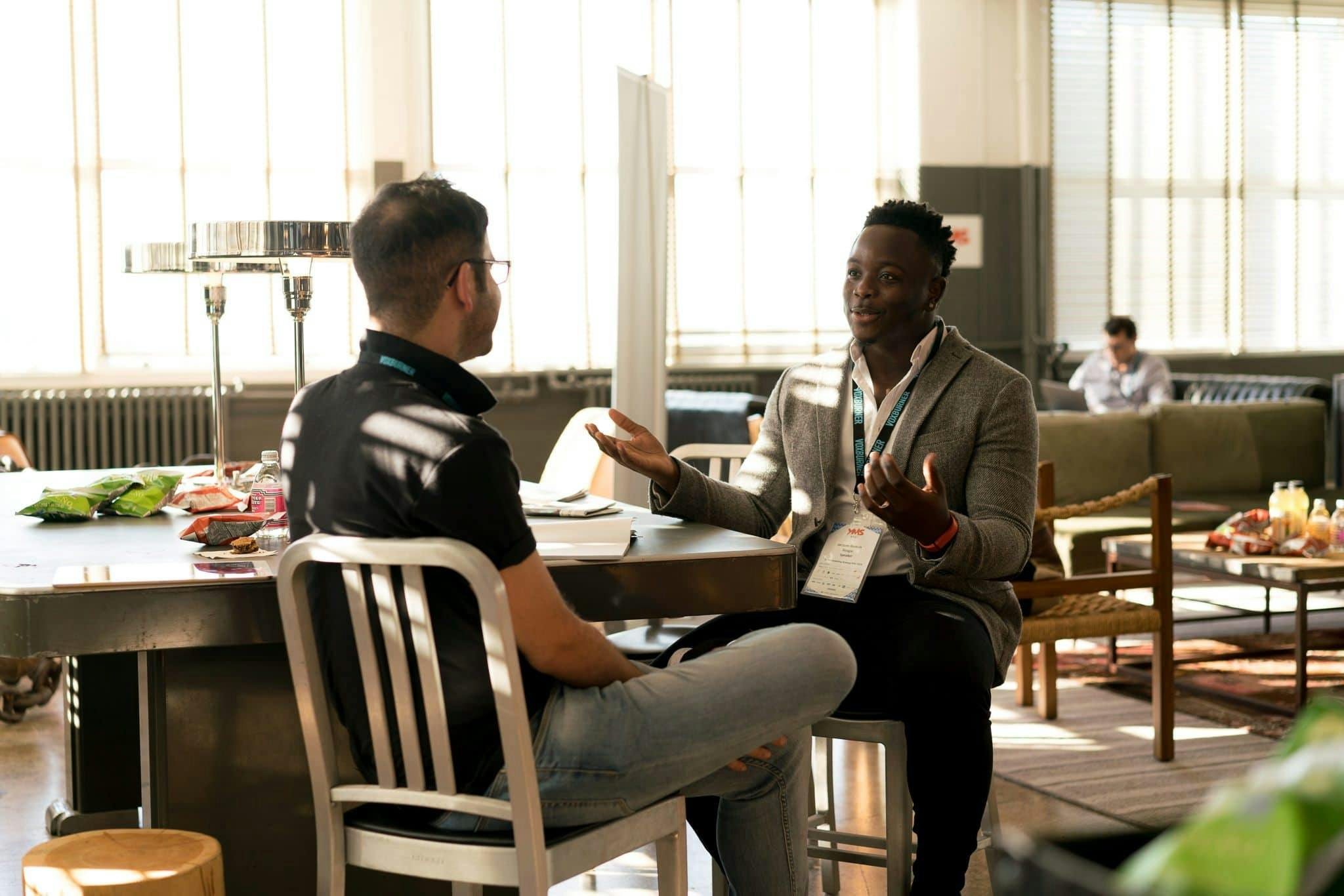 Two men having a casual discussion in a bright indoor setting, highlighting mentorship.